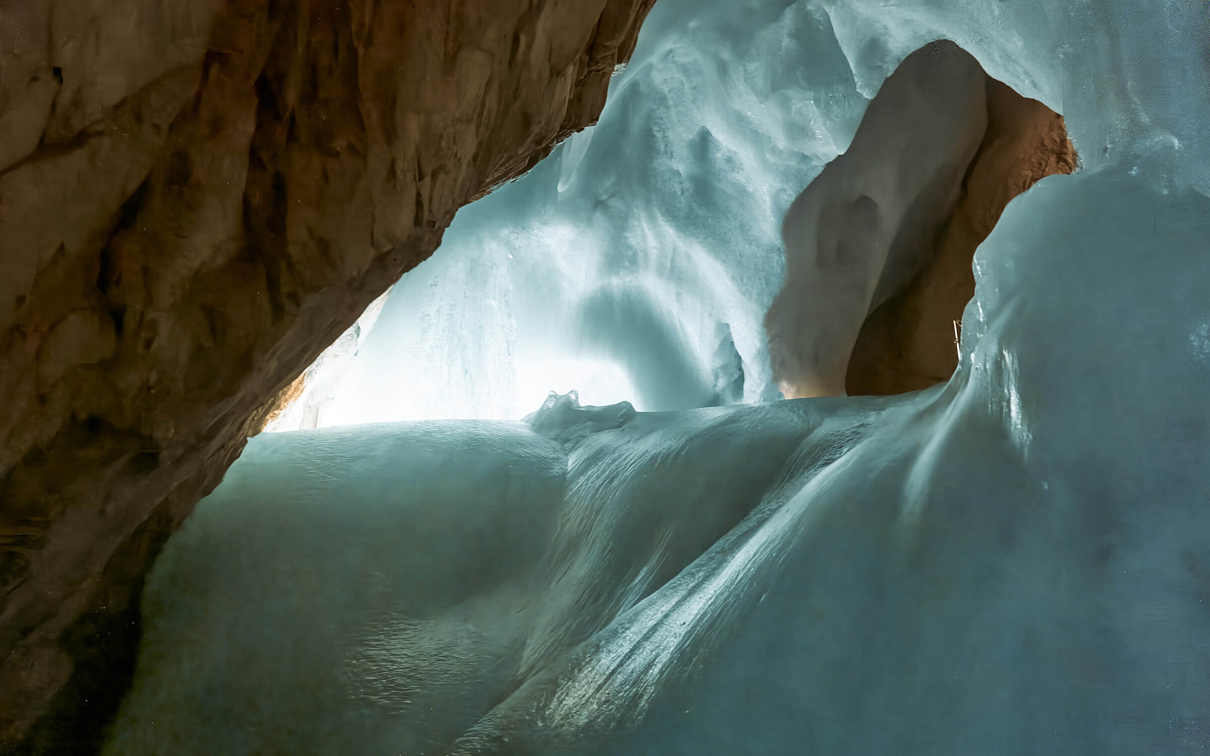 Ein Blick aus dem Inneren der vereisten Eisriesenwelt Werfen zeigt glatte, beleuchtete Eisformationen unter einer felsigen Decke,