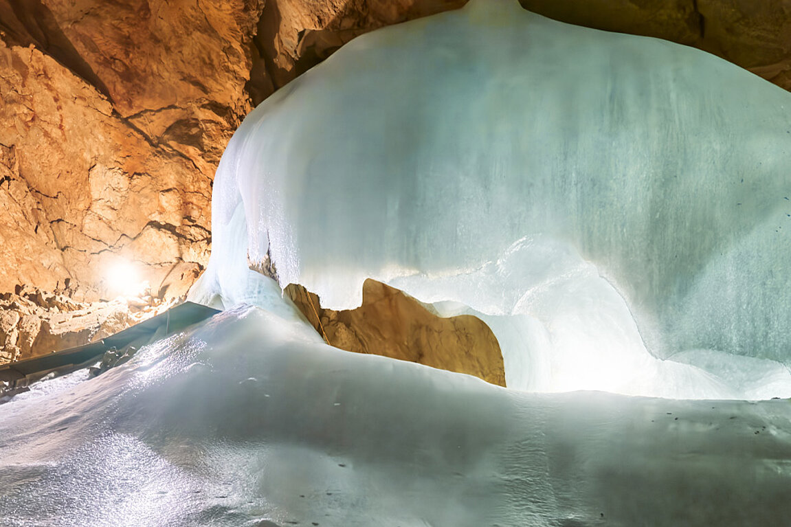 Eine Eisformation in der Eisriesenwelt, umgeben von Felswänden und von künstlichem Licht beleuchtet.