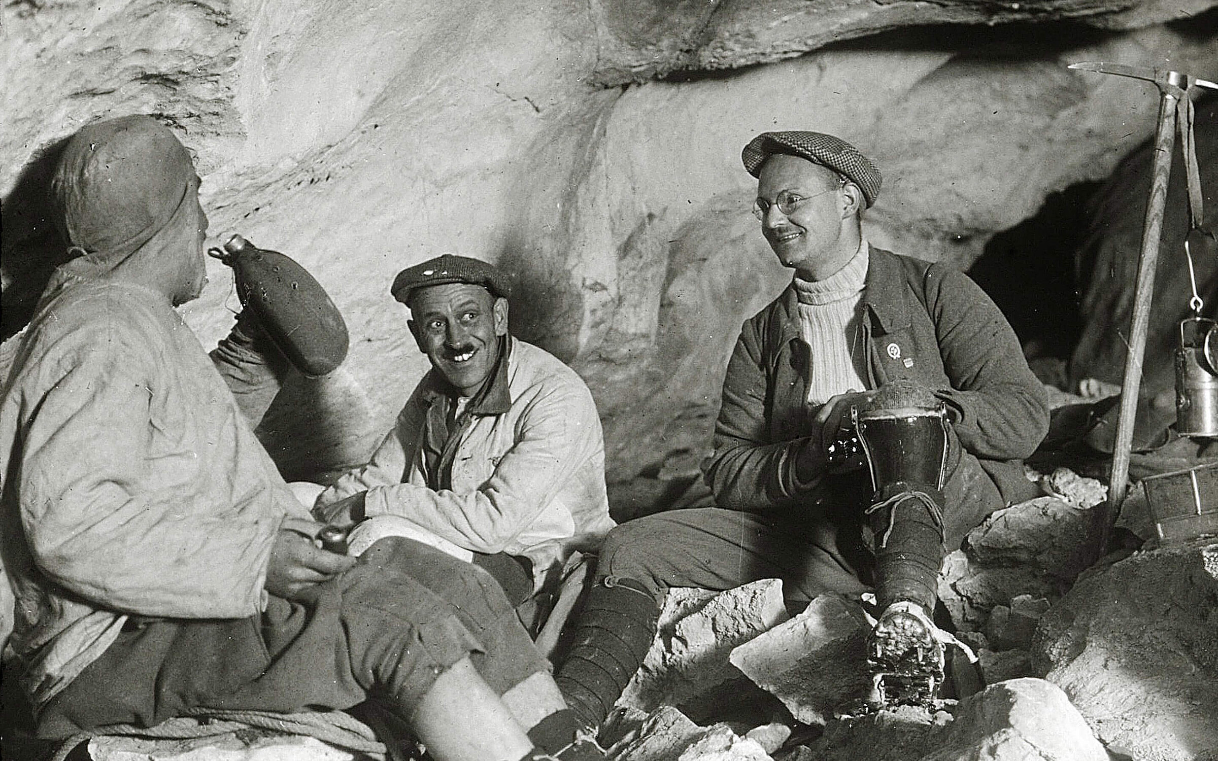 Frühe Erforscher der Eisriesenwelt Werfen: Drei Männer in historischer Kleidung rasten auf dem felsigen Höhlenboden.